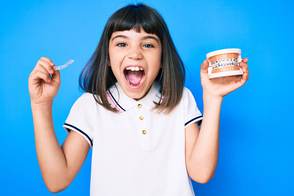 Young little girl with holding an invisible aligner